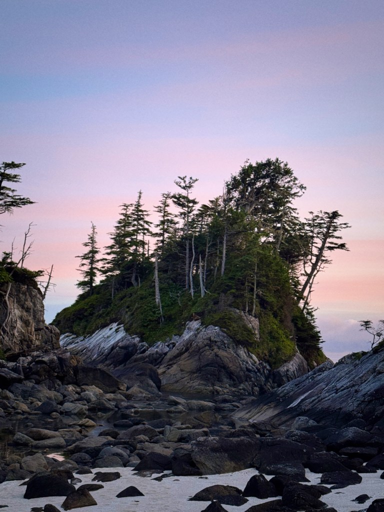 Photo showing sunset on rocky islet.